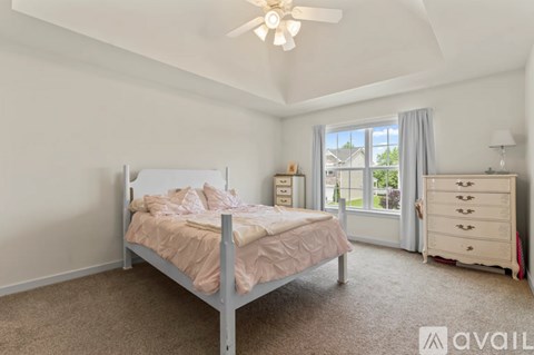 A bedroom with a bed, dresser, and window.