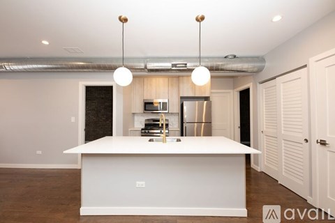 A modern kitchen with a white island and pendant lights.