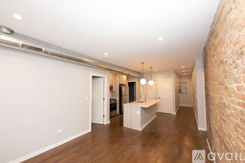 A spacious room with a brick wall on one side and a wooden floor.