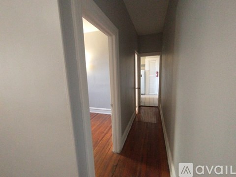 A hallway with wooden floors and white walls.