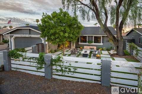 A house with a white picket fence and a tree in front.