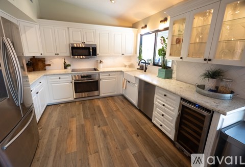 A kitchen with white cabinets and wooden floors.