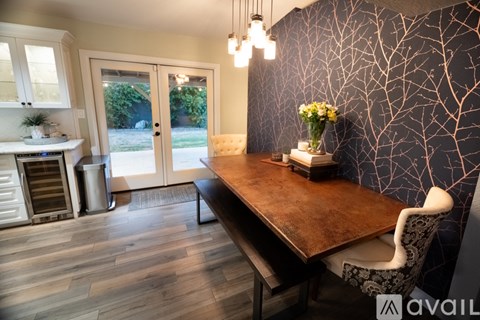 A dining room with a wooden table and a wall with a tree design.