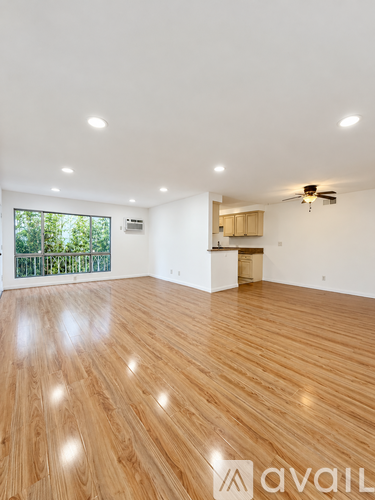 A spacious room with wooden flooring and a ceiling fan.
