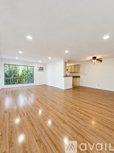A spacious room with wooden flooring and a ceiling fan.