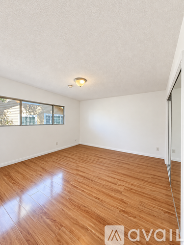 A room with wooden flooring and a window with blinds.