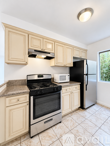 A kitchen with a black refrigerator, white microwave, and a black stove top oven.