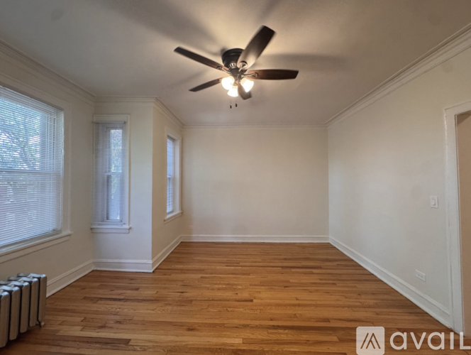 A room with a ceiling fan and wooden flooring.