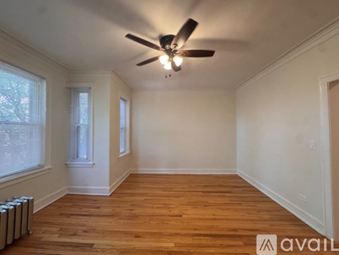 A room with a ceiling fan and wooden flooring.