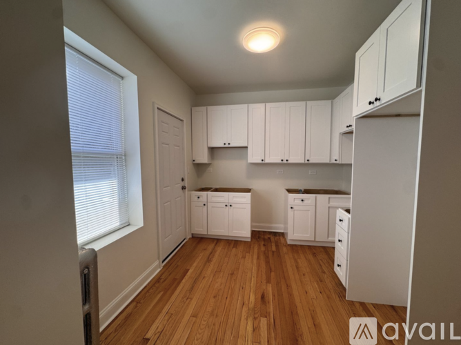 A kitchen with white cabinets and wooden floors.