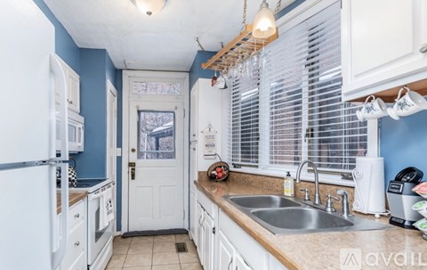 A kitchen with white cabinets and a blue wall.