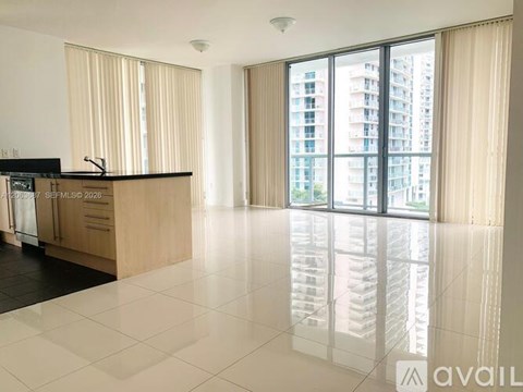 A spacious kitchen with a large island and a view of a high-rise building outside the window.