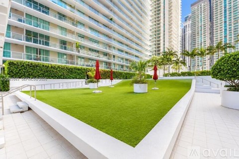 A white rectangular garden area with a white fence and red umbrellas.