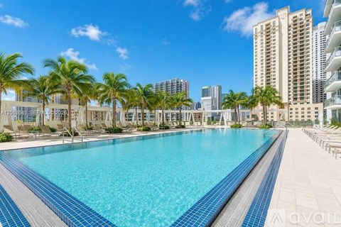 A large swimming pool surrounded by palm trees and buildings.