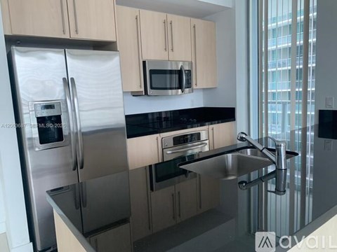 A kitchen with a stainless steel refrigerator and microwave above a stainless steel sink.