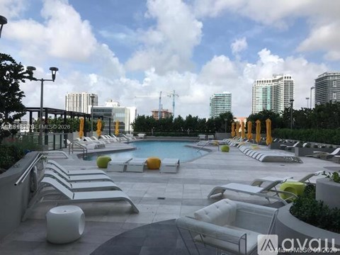 A rooftop pool area with lounge chairs and a view of the city skyline.