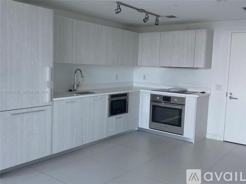 A modern kitchen with white cabinets and appliances.