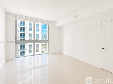 A large empty room with a view of a building outside the window.