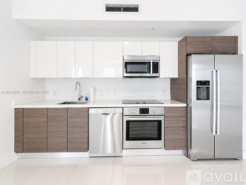 A modern kitchen with a stainless steel refrigerator, oven, and sink.