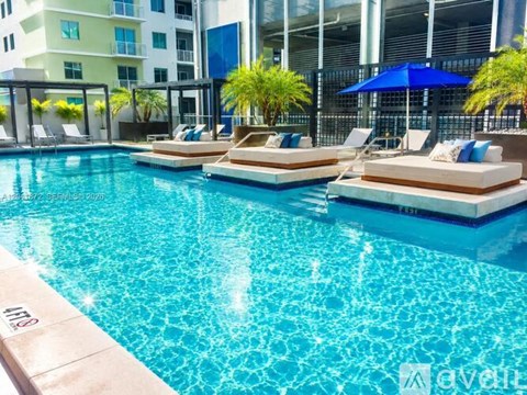 A pool with sun loungers and a building in the background.