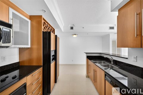 A kitchen with wooden cabinets and black countertops.