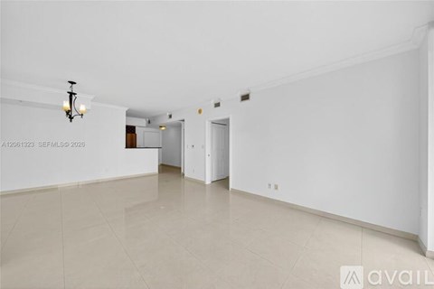 A spacious room with a light fixture on the ceiling and a door on the right.