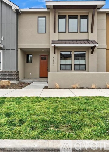 A modern house with a brown door and a small front yard.