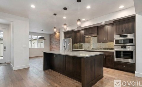 A modern kitchen with dark wood cabinets and stainless steel appliances.