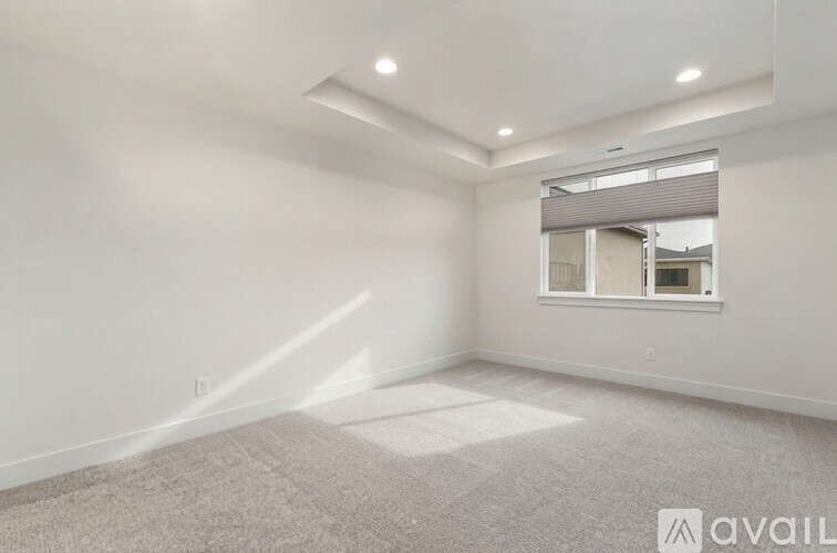 A spacious room with a window and a carpet on the floor.