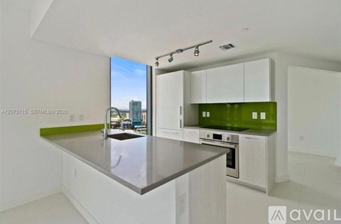 A modern kitchen with a large island and a view of the city.
