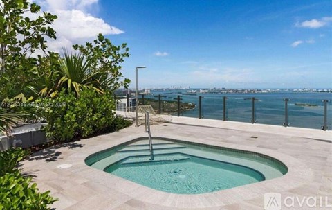 A hot tub sits in the middle of a patio with a view of the city in the distance.