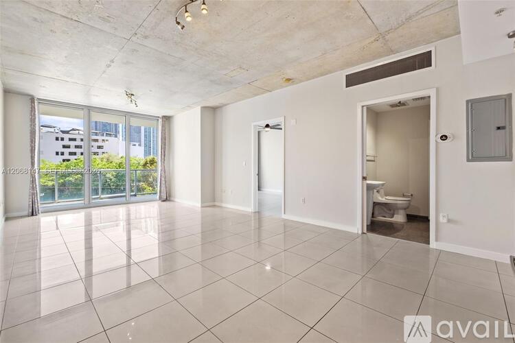 A spacious, empty room with a view of a building outside the window.