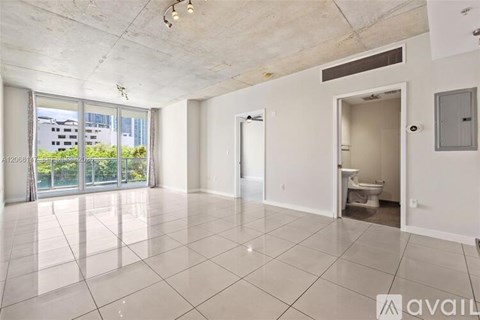 A spacious, empty room with a view of a building outside the window.