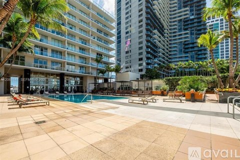 A pool area with a large swimming pool surrounded by palm trees and lounge chairs.