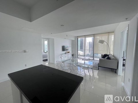 A modern kitchen with a black countertop and a glass table.