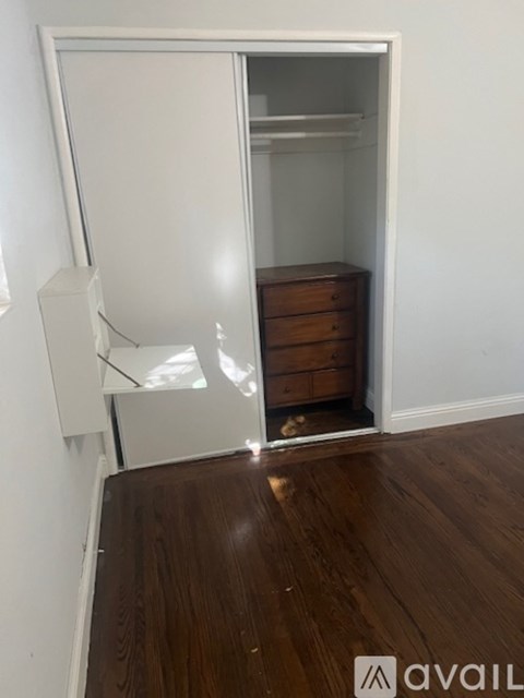 A white closet with a wooden floor and a white door.