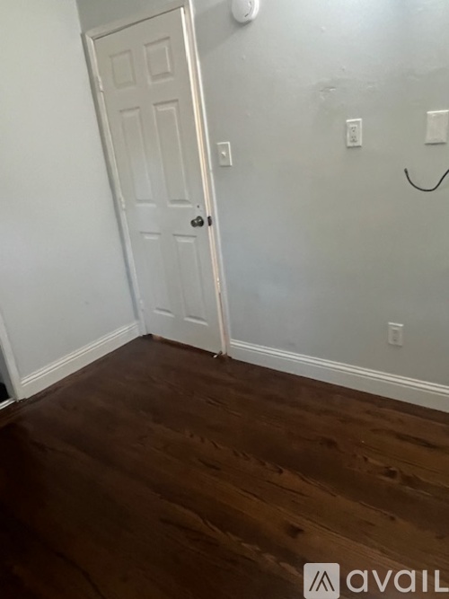 A white door is in a room with wood flooring.