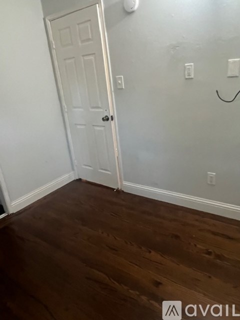 A white door is in a room with wood flooring.