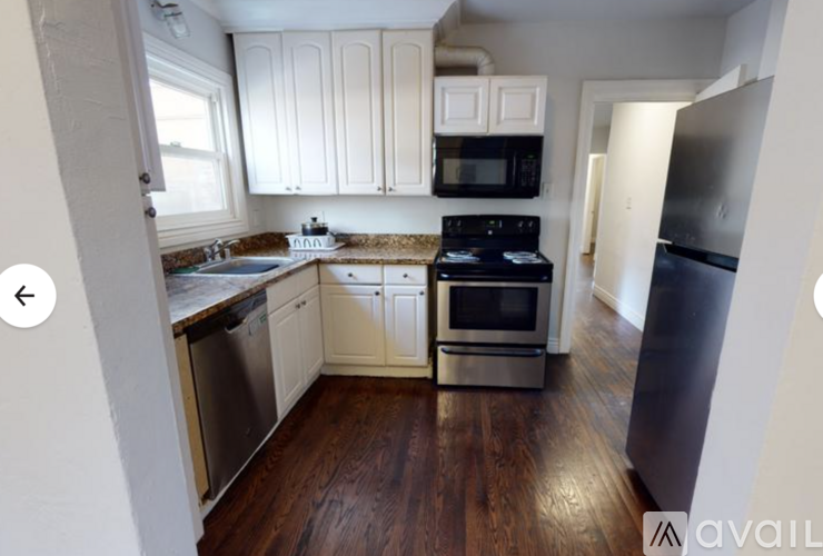 A kitchen with white cabinets and a black microwave.