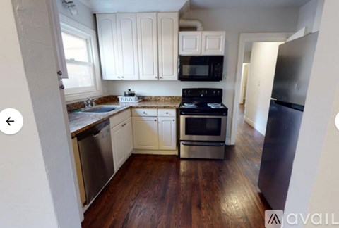 A kitchen with white cabinets and a black microwave.