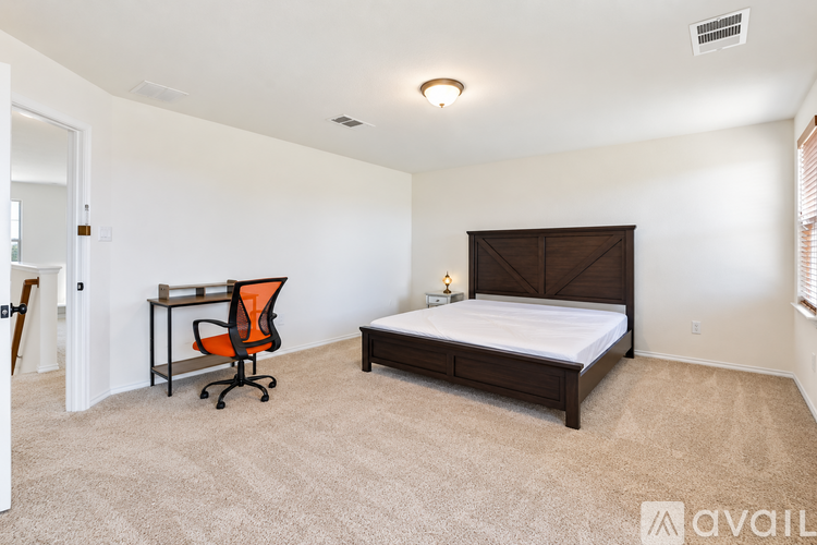 A bedroom with a bed, desk, and chair.