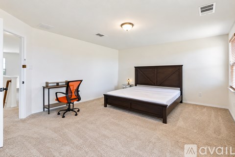 A bedroom with a bed, desk, and chair.
