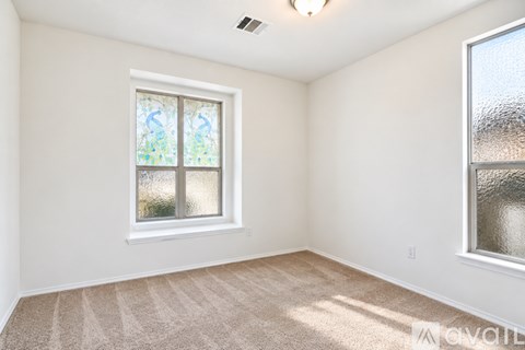 A room with a carpeted floor and a window with a view of trees.