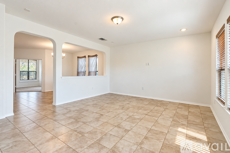 A spacious room with beige tiled flooring and white walls.
