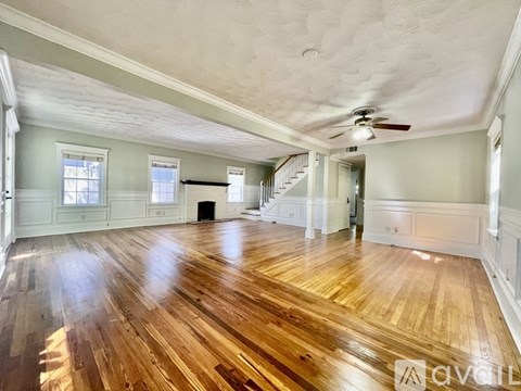 A spacious room with wooden floors and a ceiling fan.