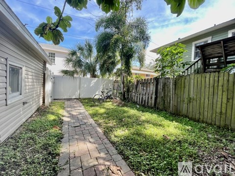A backyard with a brick walkway and a wooden fence.
