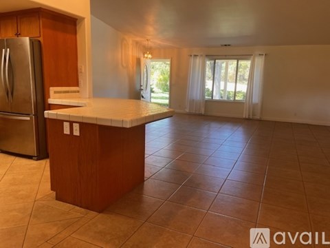 A kitchen with a refrigerator, a counter, and a tile floor.