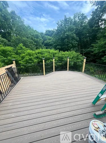 A wooden deck with a railing and trees in the background.