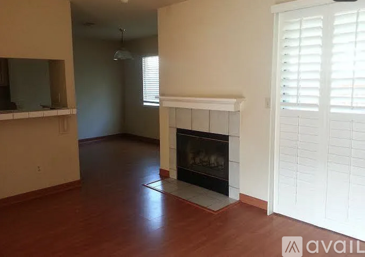A living room with a fireplace and a kitchen area in the background.