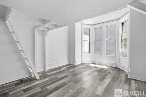 A room with a wooden floor and a white wall with a window and a door.